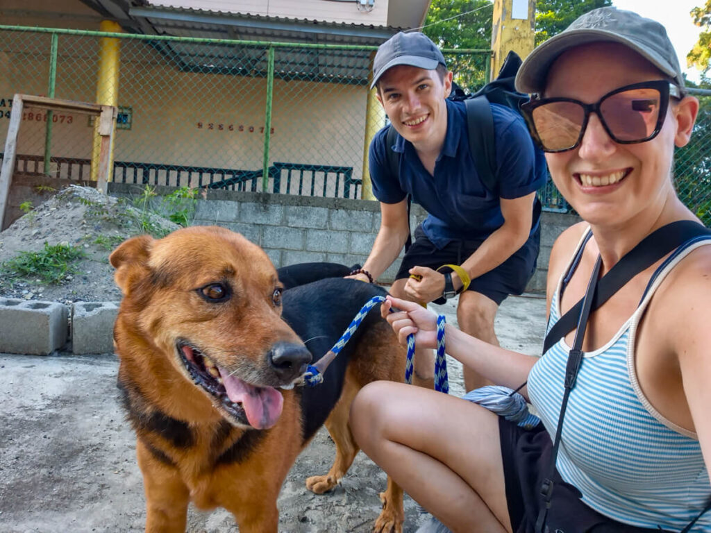 Lucy and Dan sat smiling with a dog on a lead.