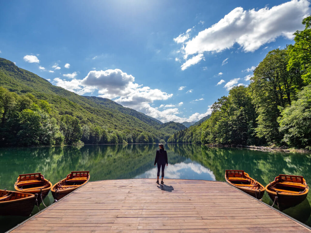 Lucy standing on the edge of a calm lake in Biogradska Gora, Montenegro.