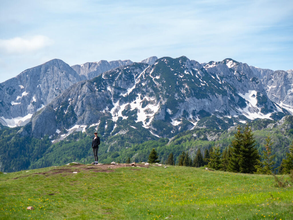 Lucy standing in front of a snowy mountain range in Durmitor National Park.