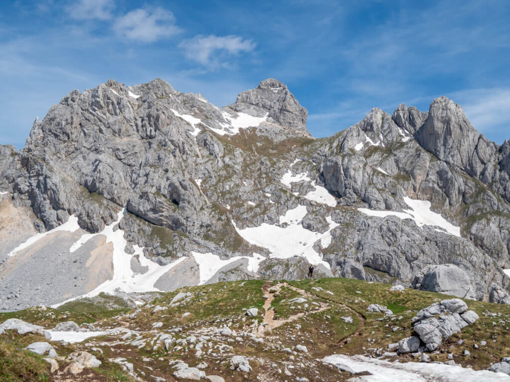 A hiking trail leading beyond a grassy ridgeline under the snowy Bobotov Kuk.