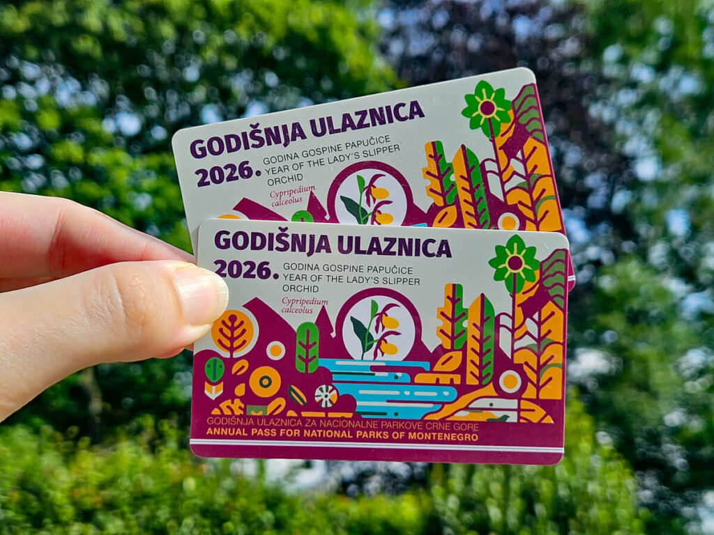 A hand holding two annual passes for Montenegro's national parks.