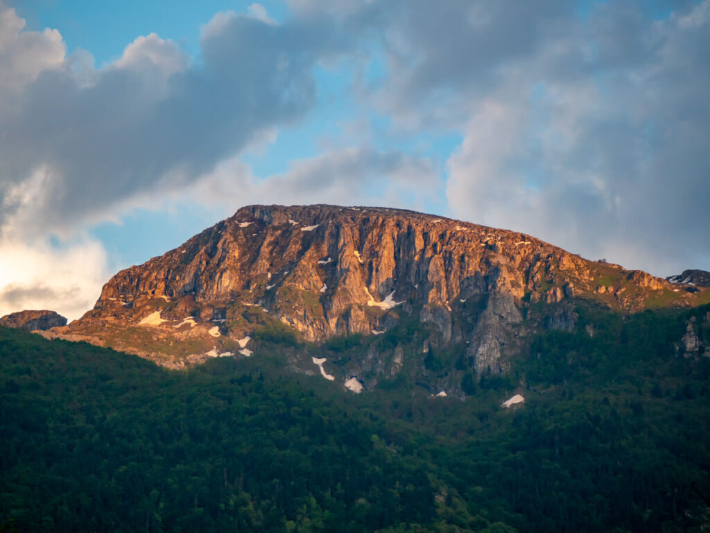 A mountain peak lit up in golden light at sunset in Prokletije National Park.