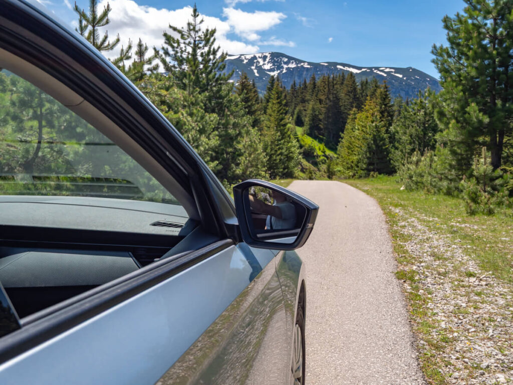 The view of snow-capped mountains down a single-track road in Durmitor National Park.