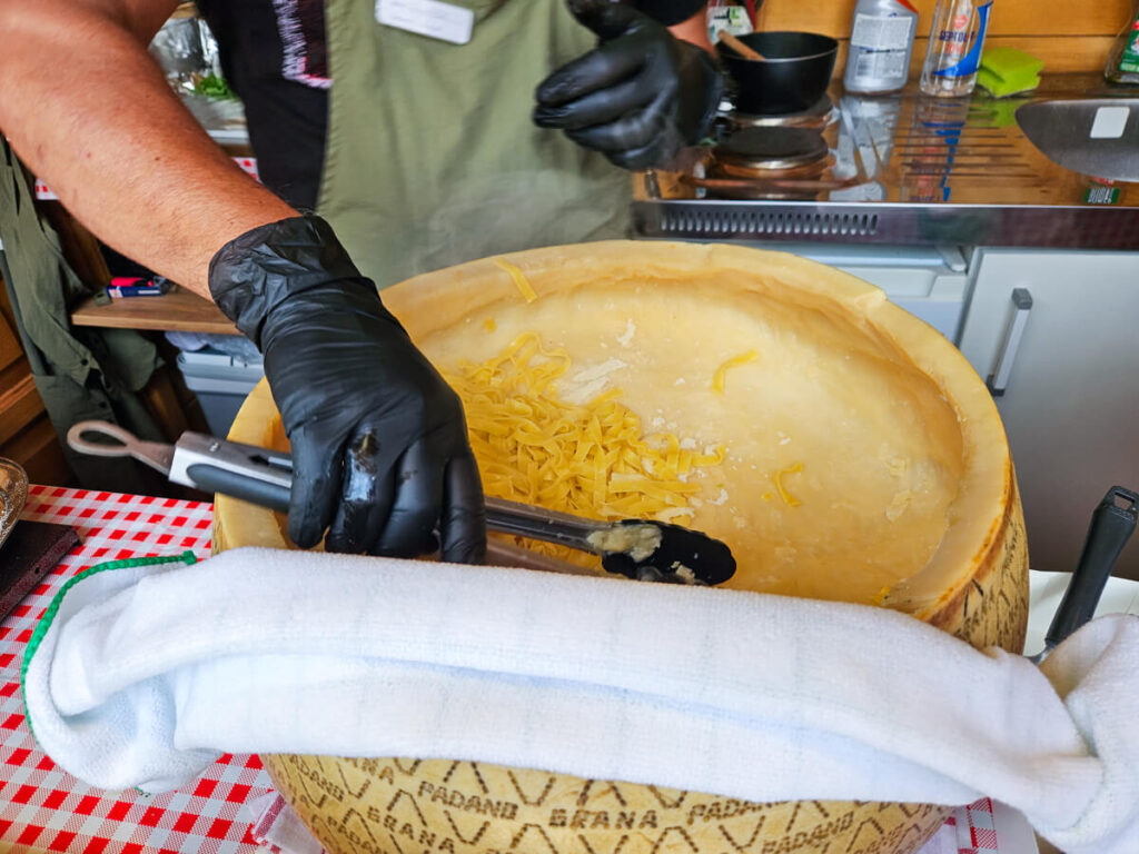 Pasta being covered in cheese inside a giant wheel of parmesan in a food hut outside Žabljak.