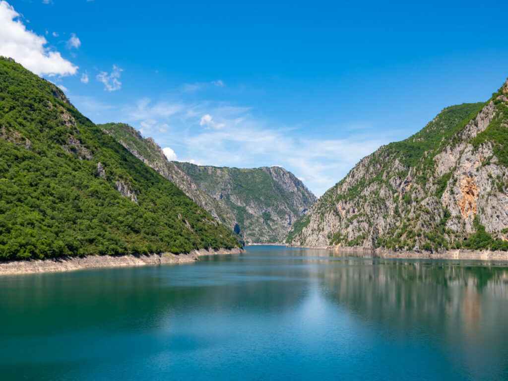 The bright blue waters of Piva Lake leading between high canyon walls.