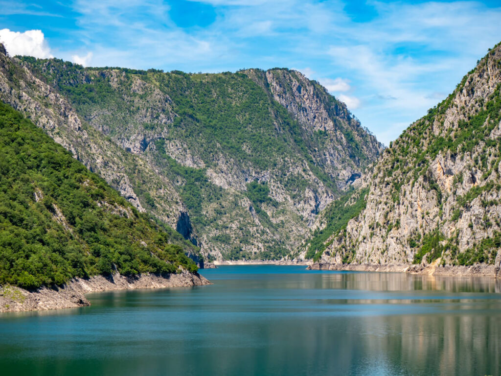 The clear and calm waters of Piva Lake backed by dramatic canyon walls.