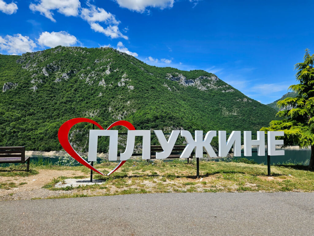 An 'I love Pluzine' sign, written in cyrillic, in front impressive mountains close to Durmitor National Park.