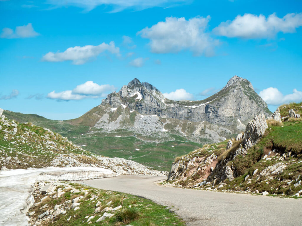 Snow by the side of a road leading to the twin peaks of Sedlena Greda in Durmitor National Park.