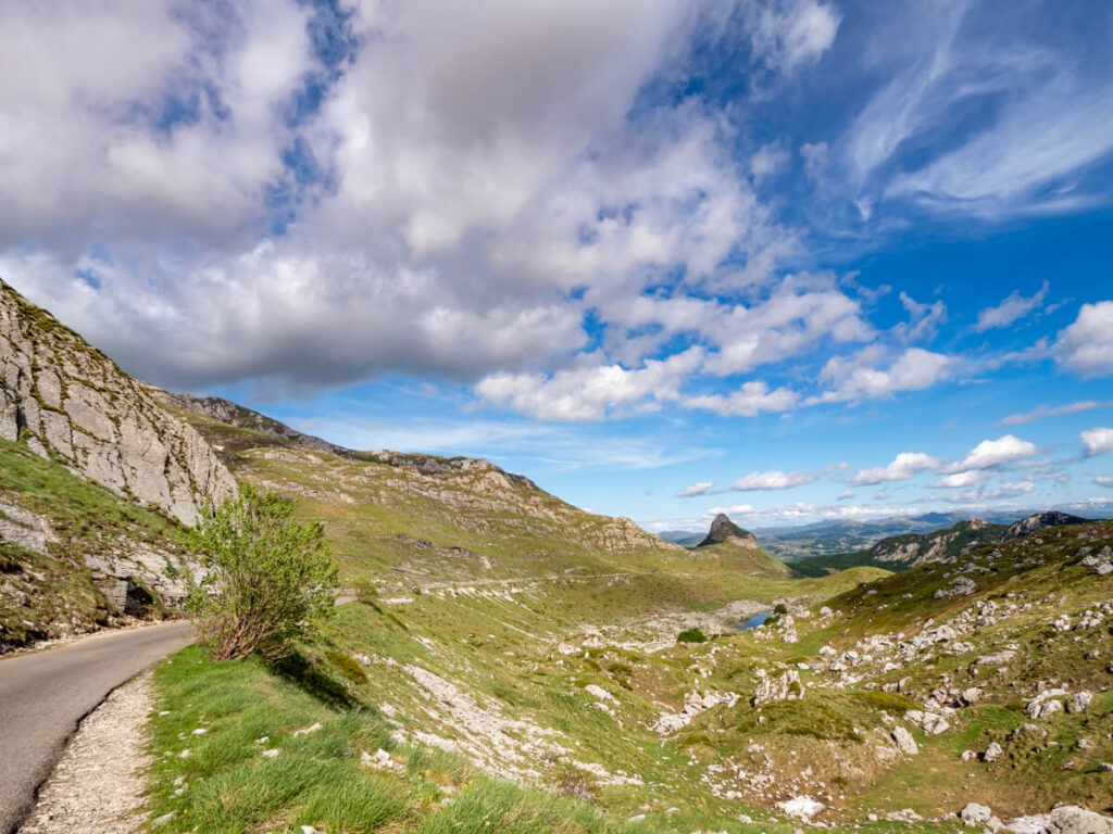 A curved narrow road leading between peaks and meadows on the Durmitor Ring.