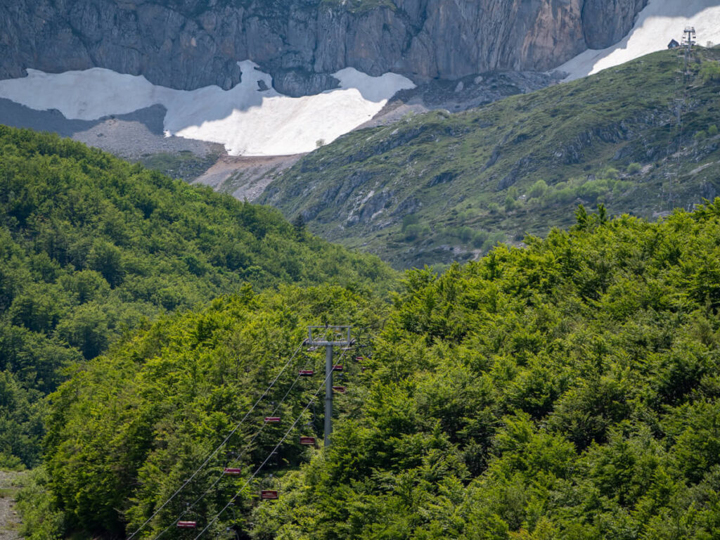 A chairlift against green trees on a snowy mountain, Savin Kuk, in Durmitor National Park.