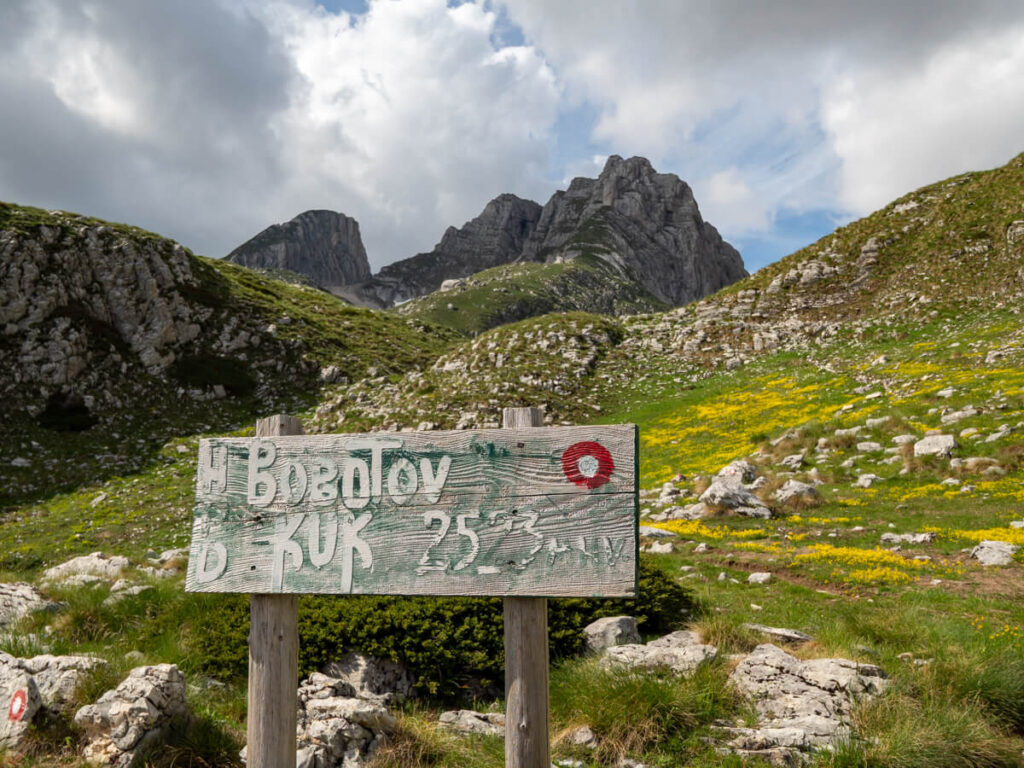 A painted wooden sign indicating the start of the Bobotov Kuk trail in Dobri Do Valley.