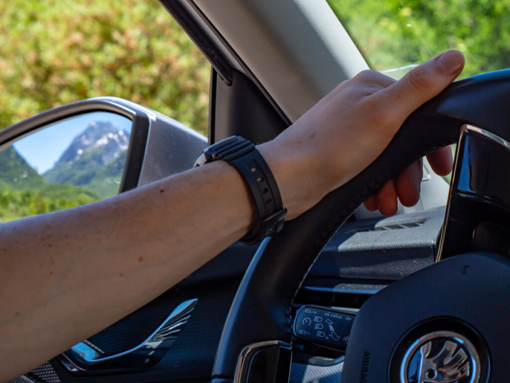 Dan's hand holding a steering wheel as he drives through the Montenegrin countryside.