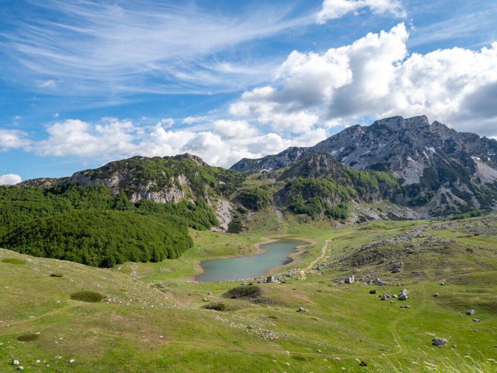 The thin blue Suva Lokva Lake in a green valley in Durmitor National Park.