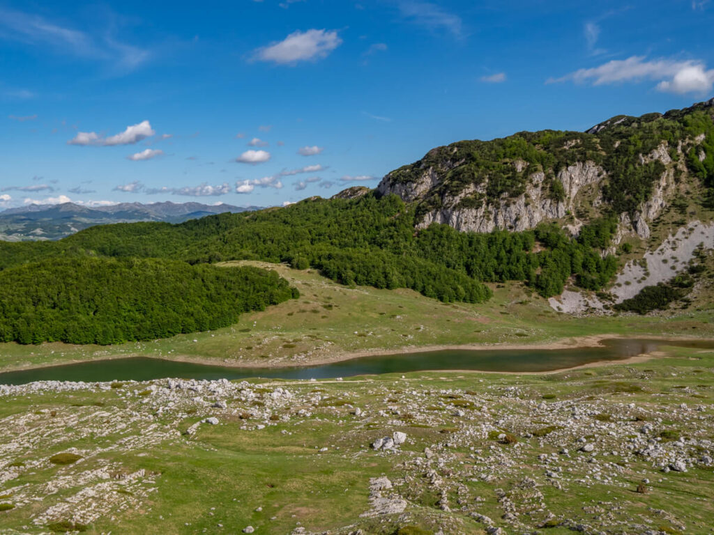 The long Suva Lokva Lake in a green valley on the Durmitor Ring Road.
