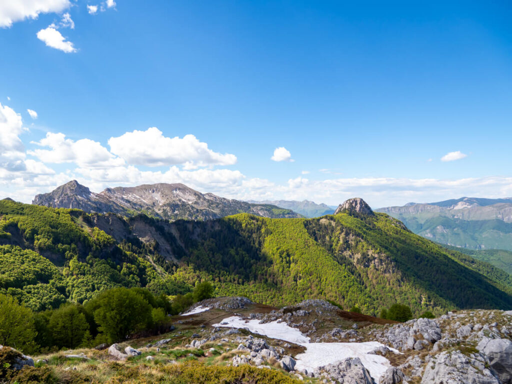Rolling hills behind a wide meadow on the Three Peaks Hike in Prokletije National Park.