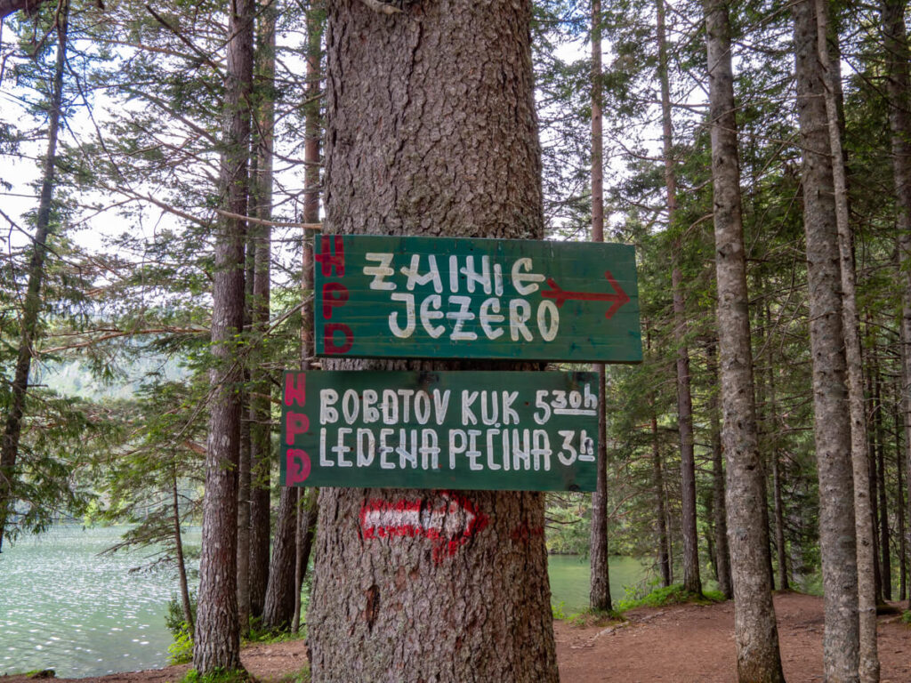 Signs for hiking trails to Bobotov Kuk and Ledena Pecina Ice Cave from the shore of the Black Lake in Durmitor National Park.