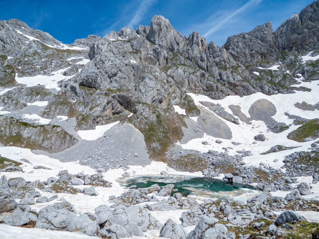 The icy blue water of Zeleni Vir glacial lake the foot of Bobotov Kuk's towering limestone peak.