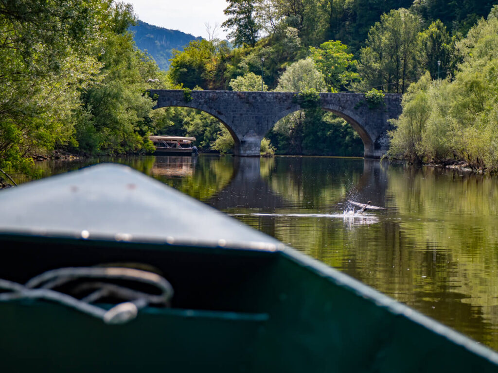 An old stone bridge over the river in Rijeka Crnojevića, viewed from a boat.