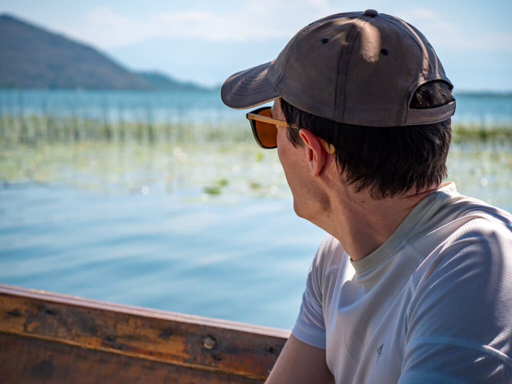 Dan looking away at reeds on a wooden boat on a trip on Lake Skadar.