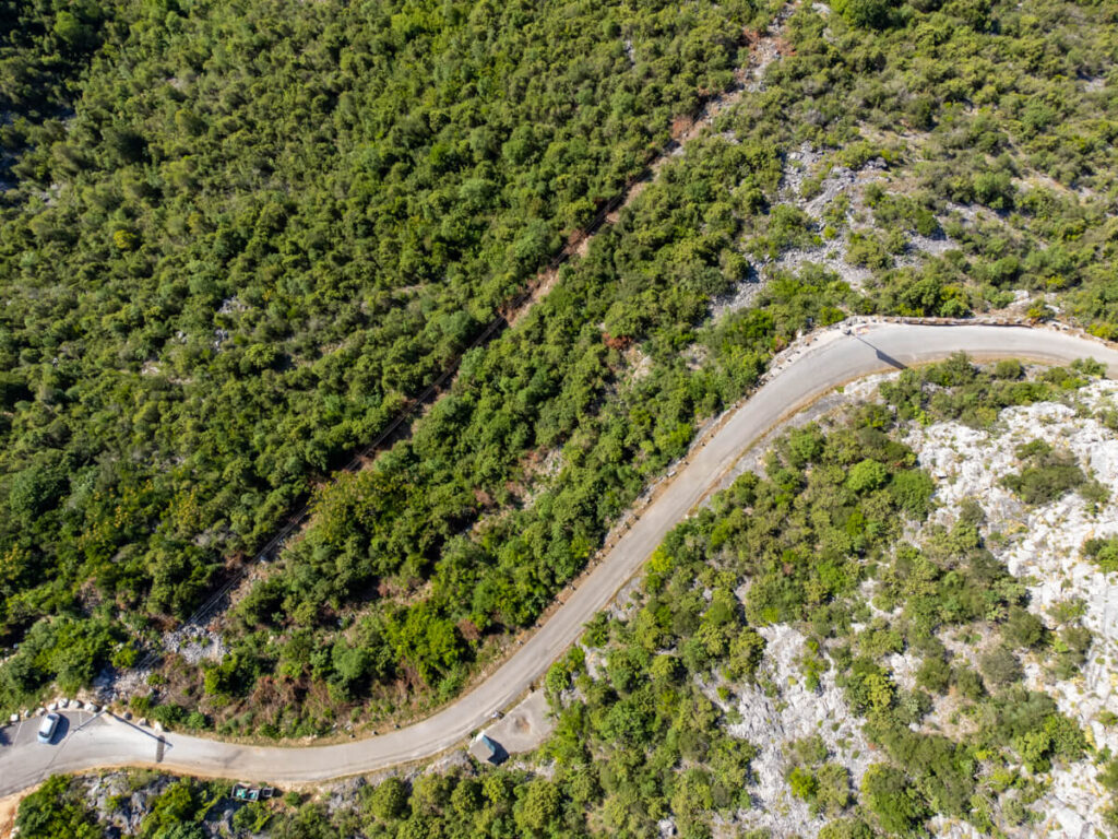 A winding road surrounded by greenery, photographed by drone.
