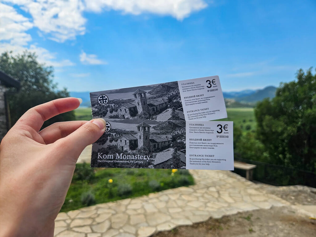 Lucy's hand holding tickets for Kom Monastery in Montenegro.