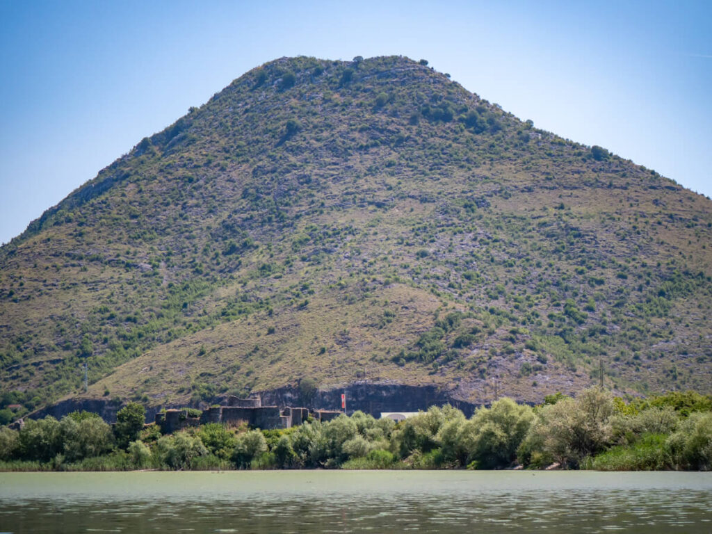 Lesendro Fortress in the distance at the foot of a tall mountain.