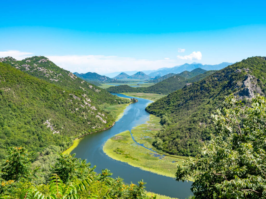 A river winding its way between tree-covered montains, as viewed from Pavlova Strana.