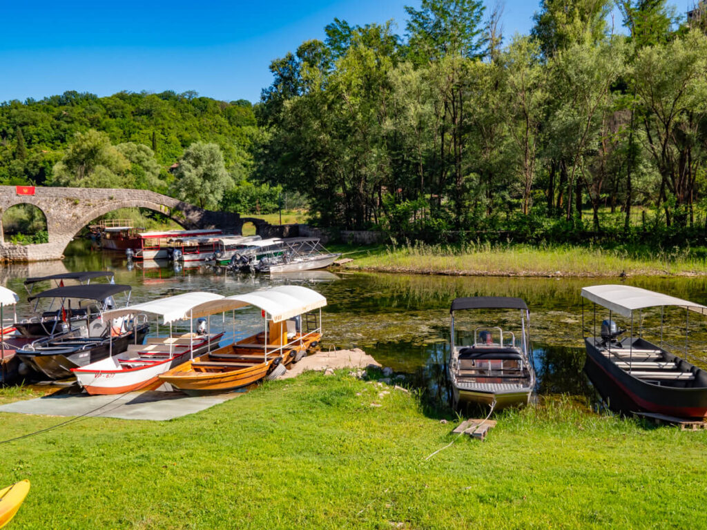 Boats docked on shore of the river that runs through Rijeka Crnojevića.