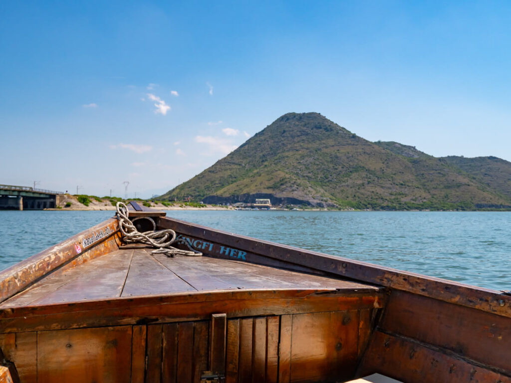 A large mountain viewed from a small wooden boat on Lake Skadar.