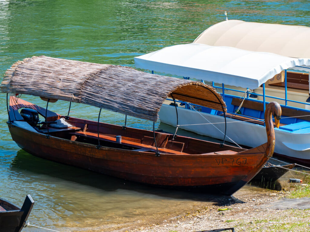 A traditional wooden boat beached on the bank of a river in Virpazar, Montenegro.