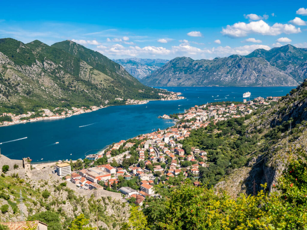 A panoramic view of the blue Bay of Kotor lined by Kotor's Old Town, viewed from the Ladder of Kotor hike.