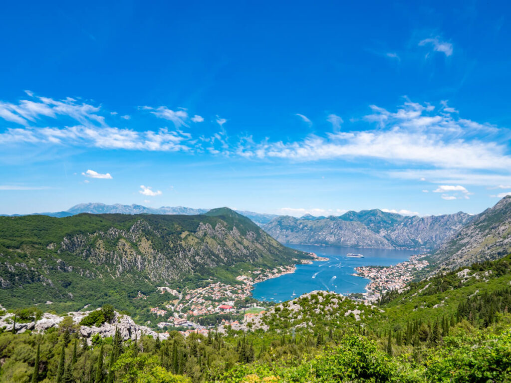 An expansive view of the Bay of Kotor surrounded by mountains covered in greenery.
