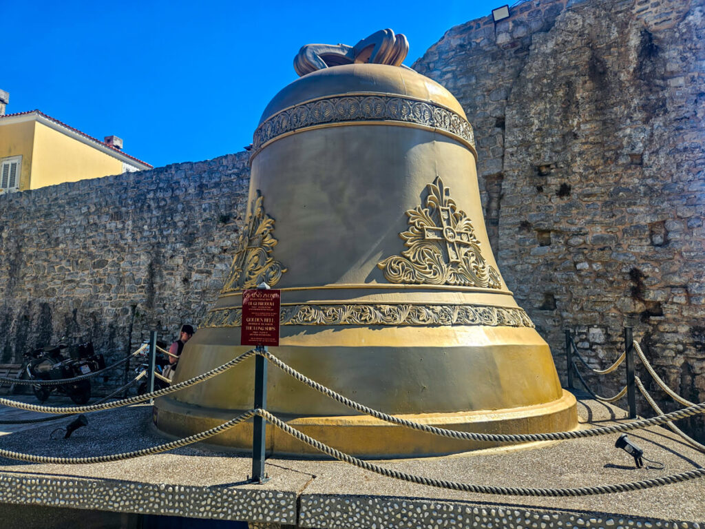 A large gold bell outside the walls of Budva Old Town.