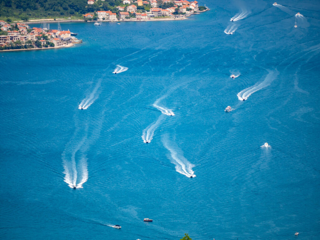 Speedboats leaving white trails in the blue waters of the Bay of Kotor.