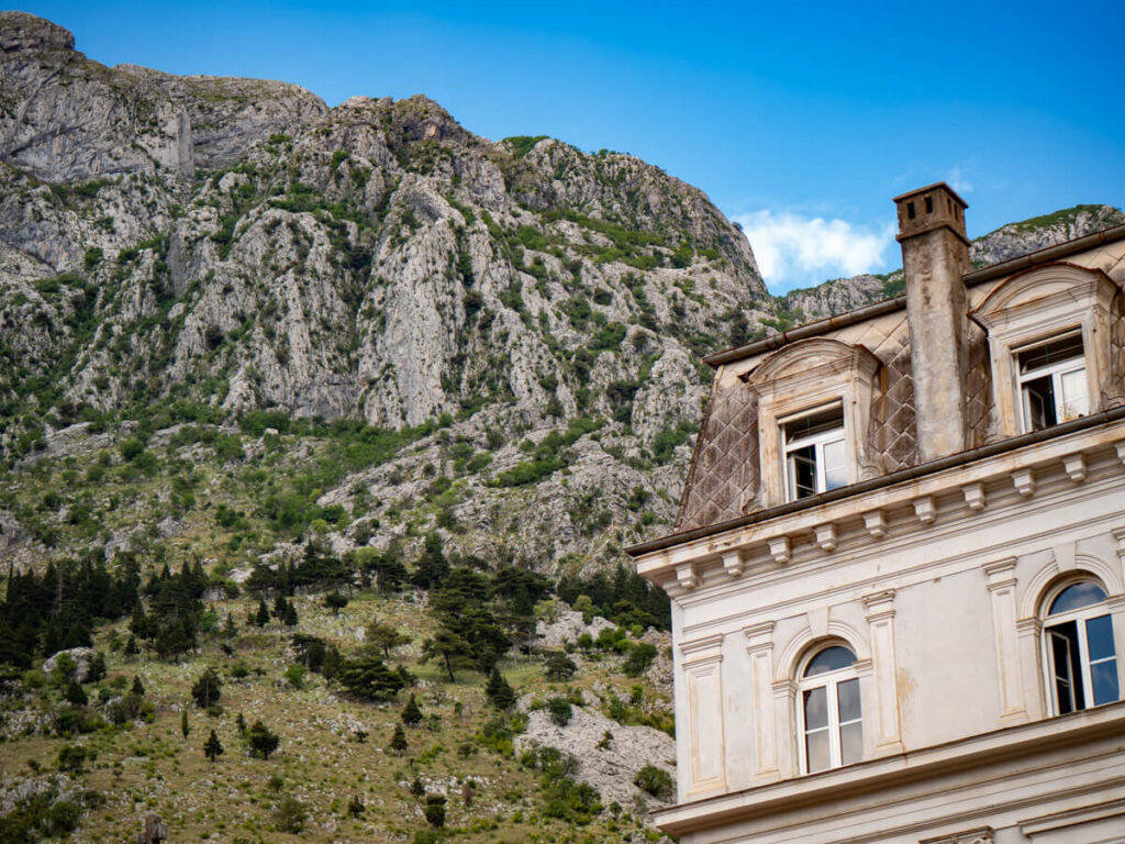 A stone building backed by rocky hills on the outskirts of Kotor's Old Town.