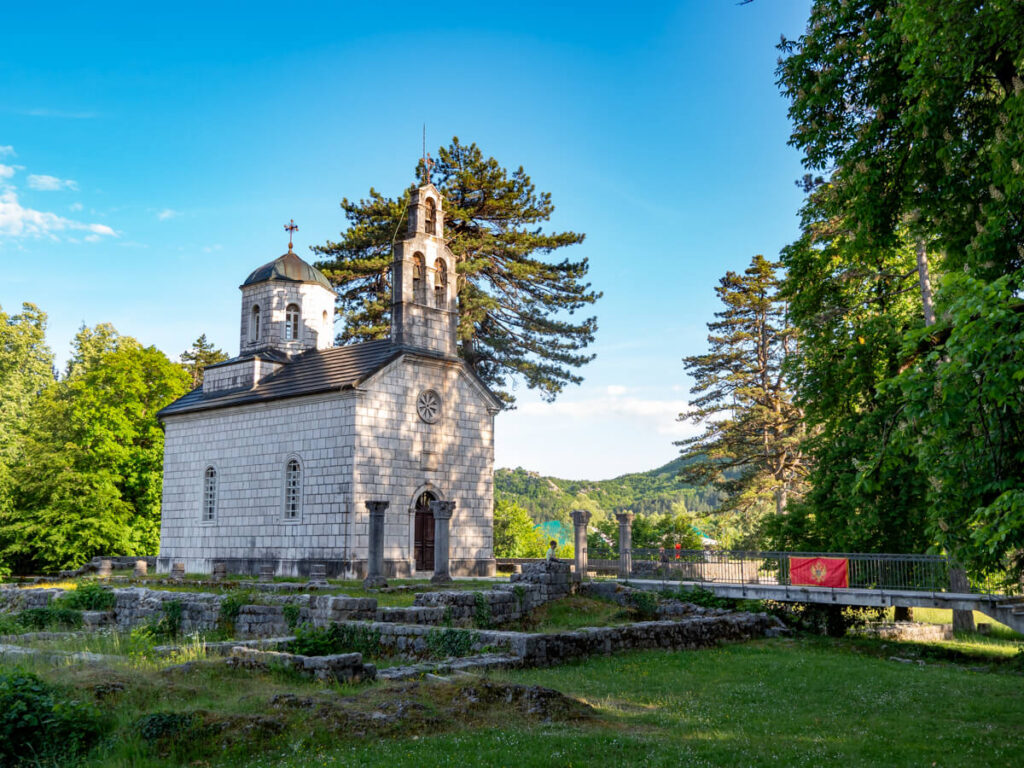 The small Court Church at Ćipur surrounded by greenery and stone ruins.