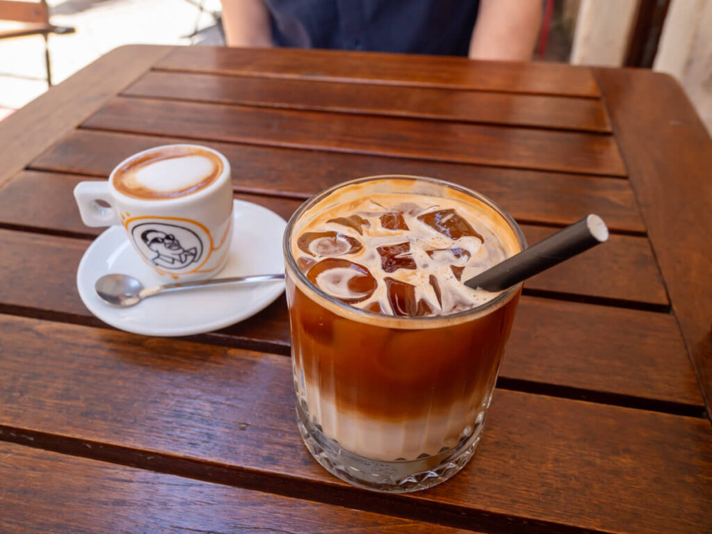 Two coffees, one iced, one cappuccino, on a table at Mon Bistro, one of the best cafés in Kotor.