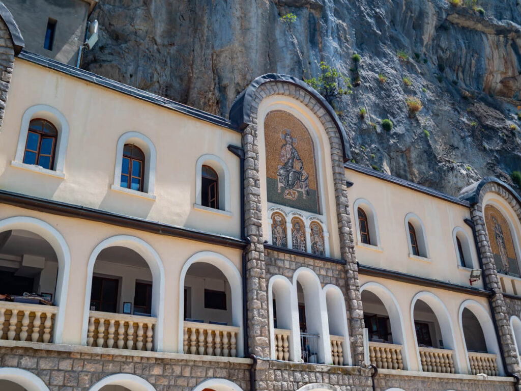 The arched fadace of part of the Upper Monastery of Saint Basil of Ostrog with a gold mosaic in the central arch.
