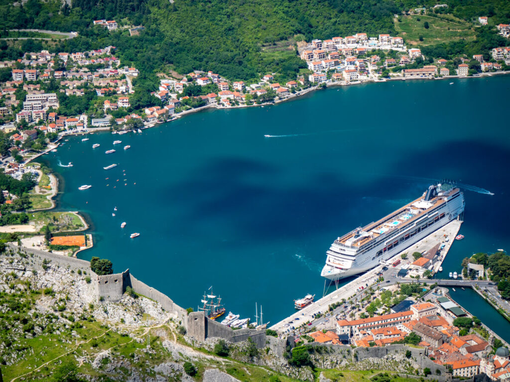 The walls of San Giovanni Fort leading downhill to a cruise ship docked in the port in Kotor, viewed from above on the Ladder of Kotor.