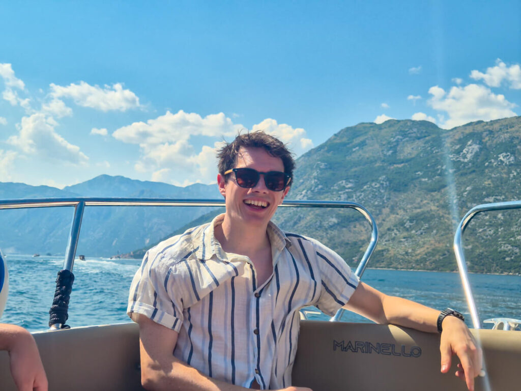 Dan smiling on the front of a speedboat in the Bay of Kotor.