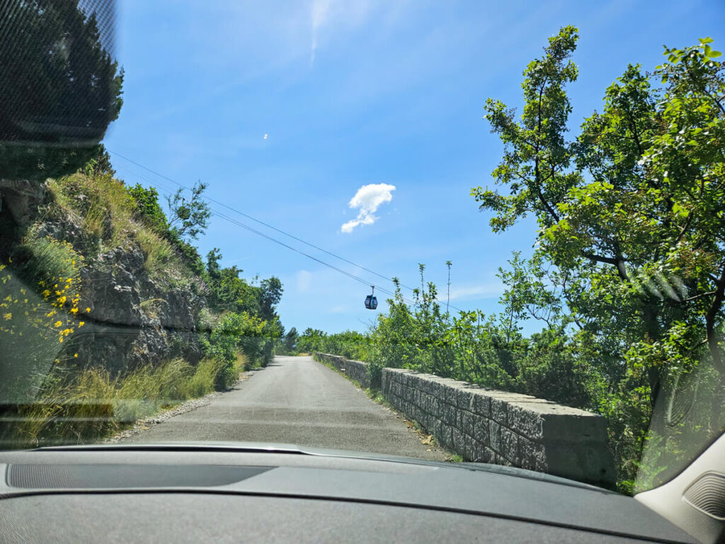 A road leading under a cable car along the Kotor Serpentine route. viewed through a car's windshield.