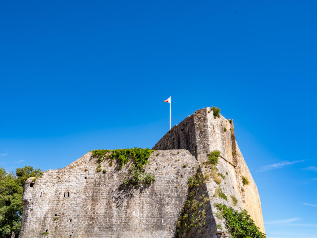A flag on top of the large stone Budva Old Town walls.