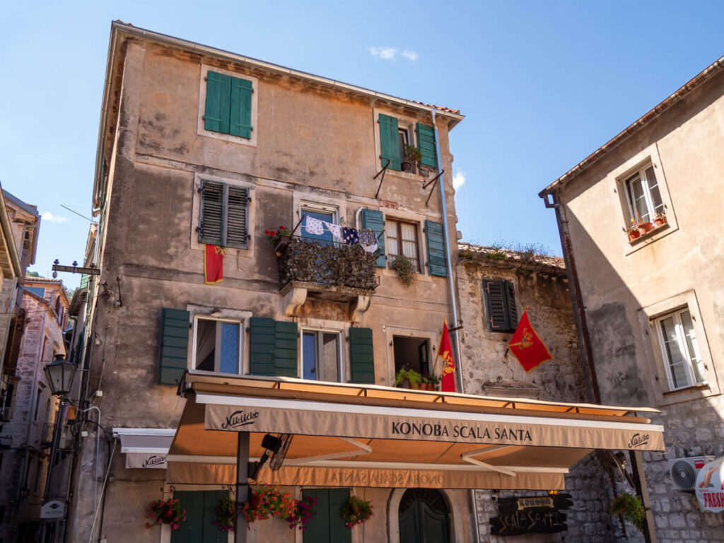 A restaurant with an awning reading "Kenobo Scala Santa" overlooking a square in Kotor's Old Town.