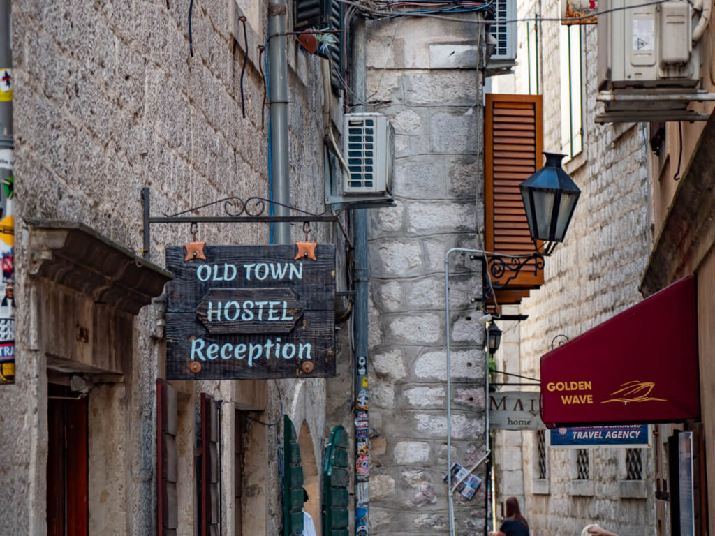 The stone-clad Craftsnen Street in Kotor and a sign reading "Old Town Hostel Reception".