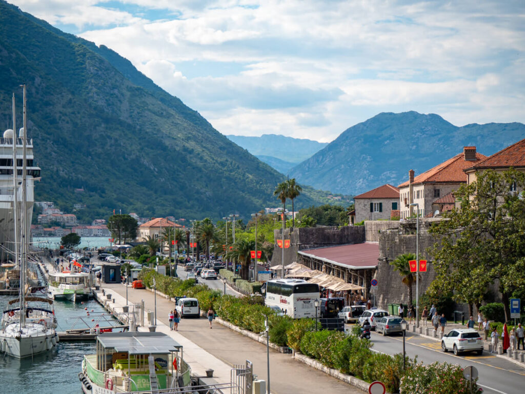 Boats docked along Kotor's waterfront, parallel to the main road through the town.