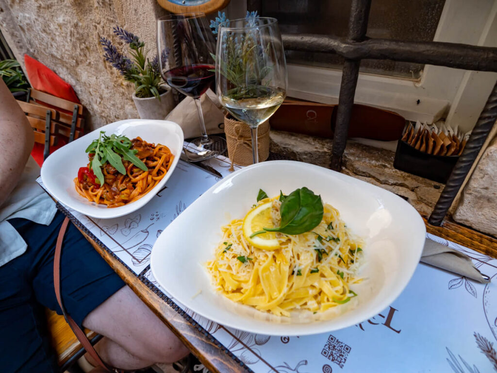 Two bowls of fresh pasta and two glasses of wine at the highly-recommended La Catedral Pasta Bar in Kotor.