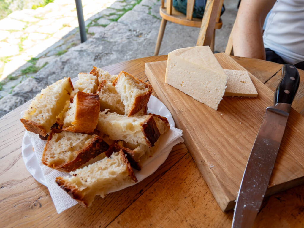 Bread and a big wedge of cheese on a table in the Cheese Shop on the Ladder of Kotor.