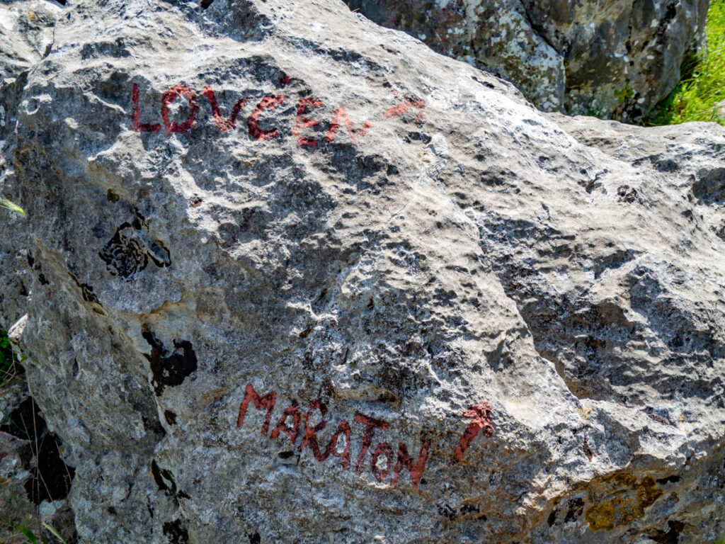 A rock with red paint pointing the ways to Maraton and Lovcen.