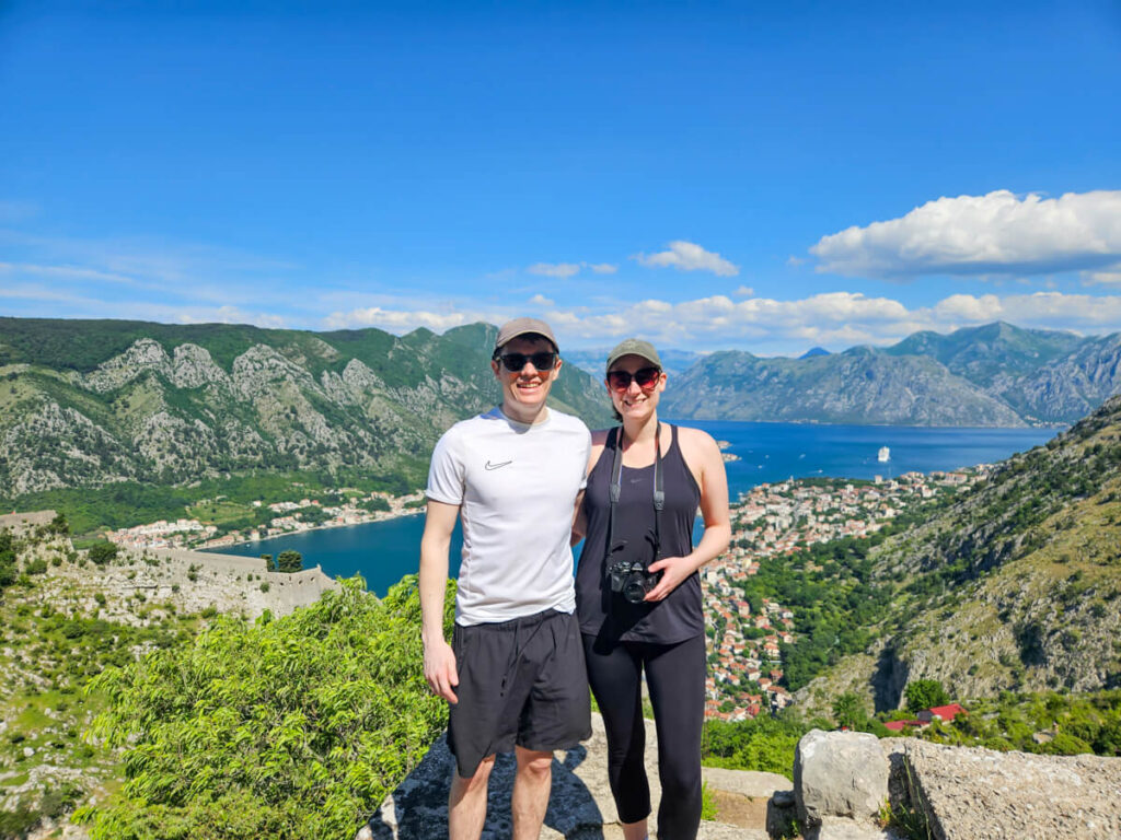 Lucy and Dan standing on a concrete platform in front of expansive views of the Bay of Kotor.