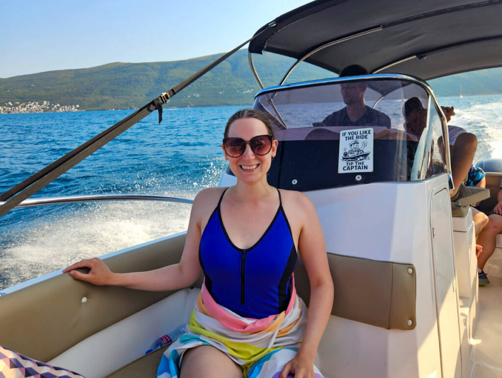 Lucy wearing a swimming costume and towel on a speedboat zipping through the Bay of Kotor.